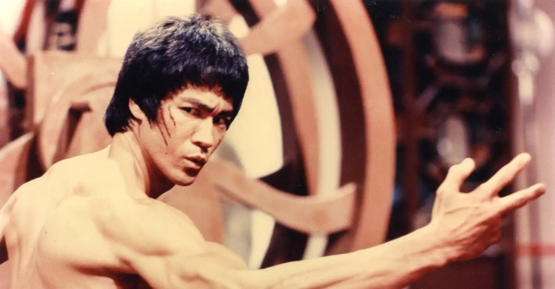 A martial artist in a yellow jumpsuit executing a fighting stance with an outstretched arm.