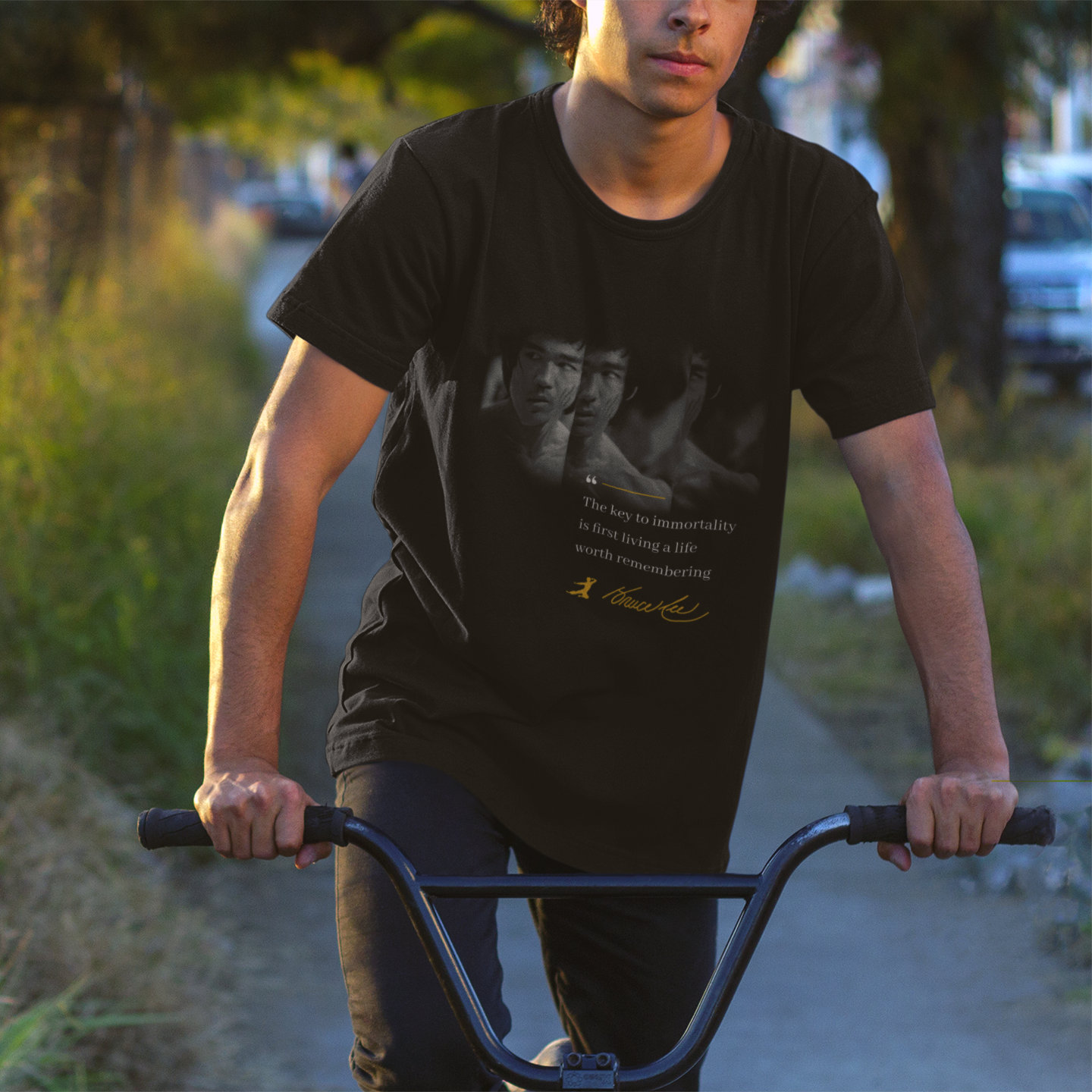 Person in a black Immortality Bruce T-Shirt riding a bicycle inspired by Bruce Lee