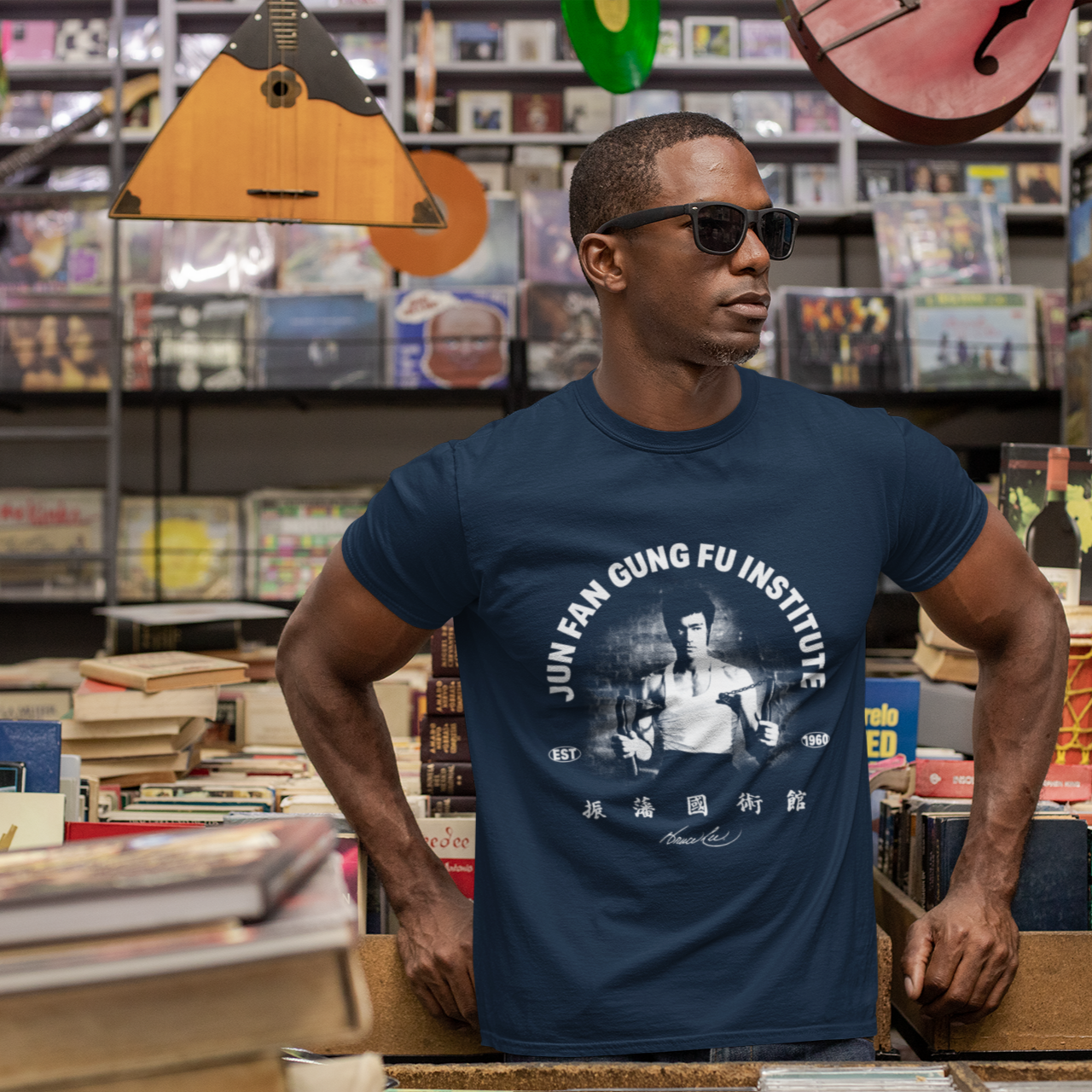 Man in blue Bruce Lee JFGFI T-Shirt browsing records in a store