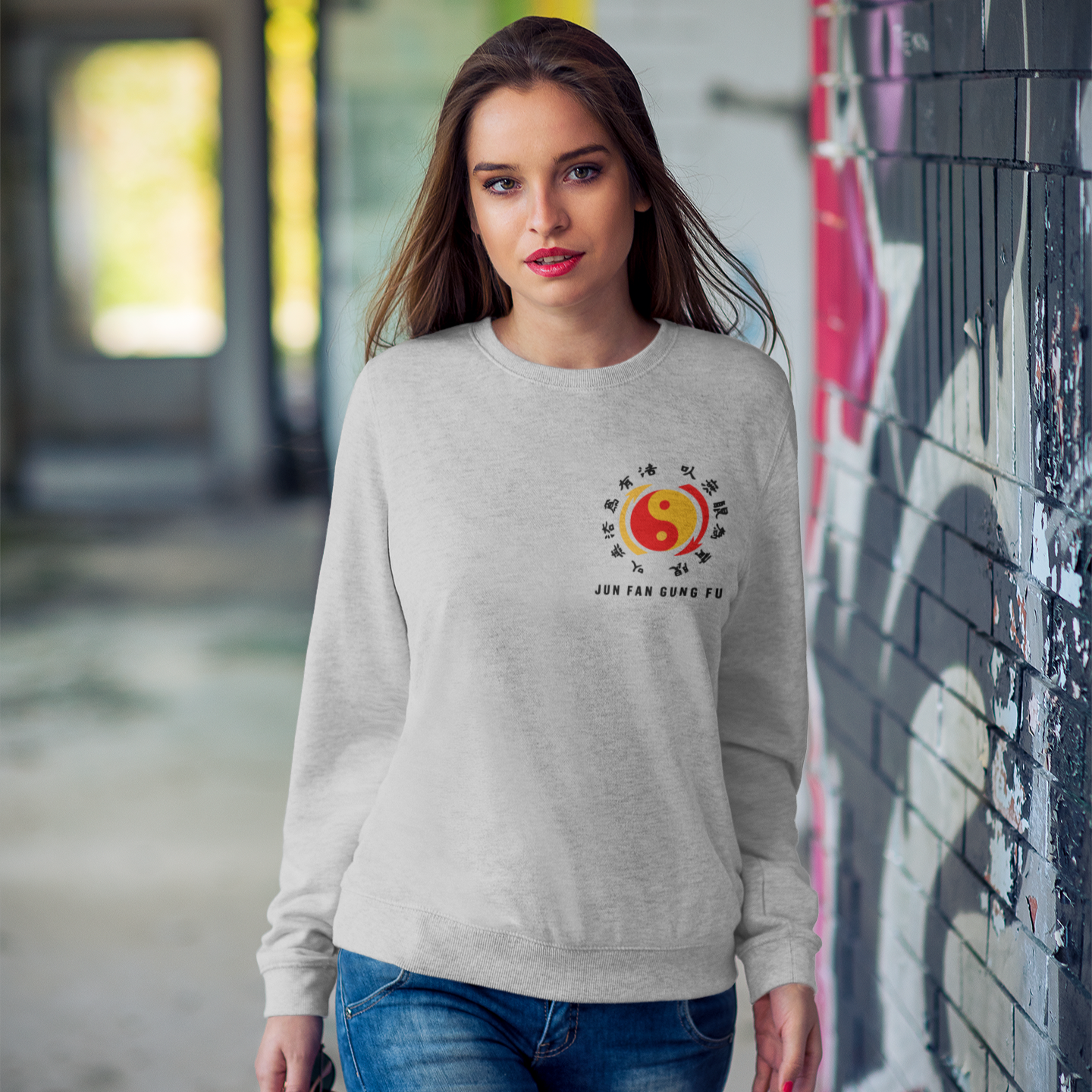 Woman in a white Jun Fan Gong Fu Sweatshirt with colorful sun design and text